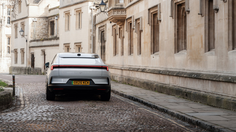 Rear view of a Polestar 4 on a cobblestone street next to a stone building